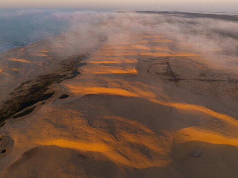 Fog and sunlit Sand dunes by the ocean. 