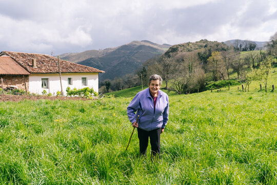 Elderly cheesemaker woman standing in green rural field