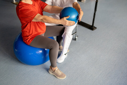 Senior woman exercising with rehabilitation ball and therapist