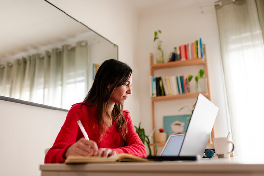 Focussed Woman teleworking using laptop and notebook