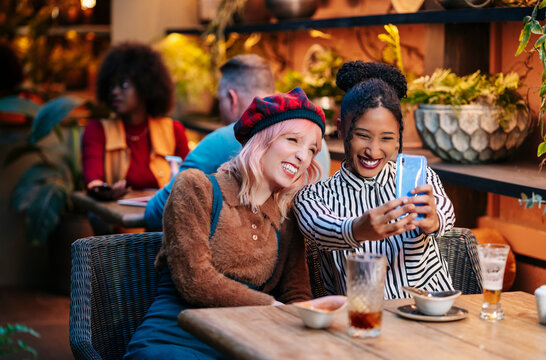 Happy young women taking selfie at bar restaurant