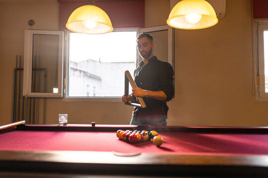 Man arranging billiard balls before game