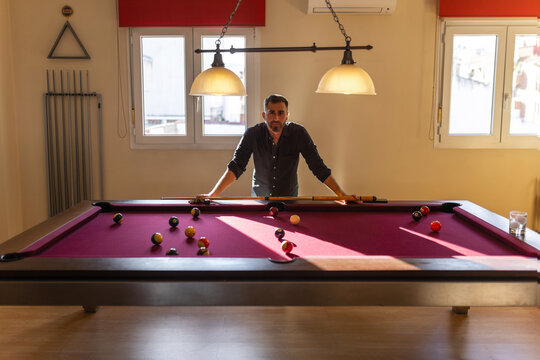 Man standing and observing billiard table at home