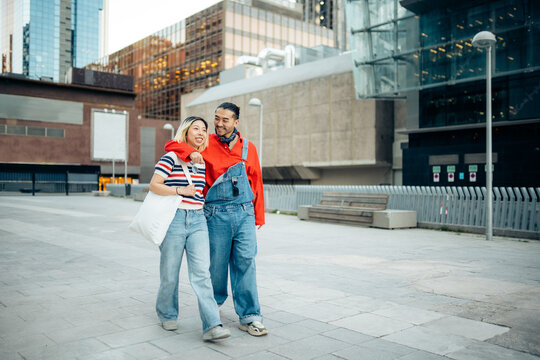 Young couple walking together embracing in city