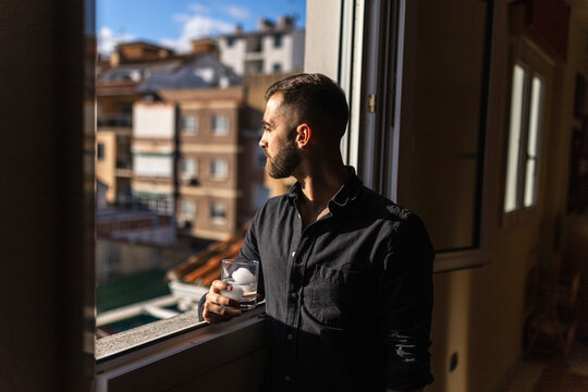 Man holding drink by window in relaxed home moment