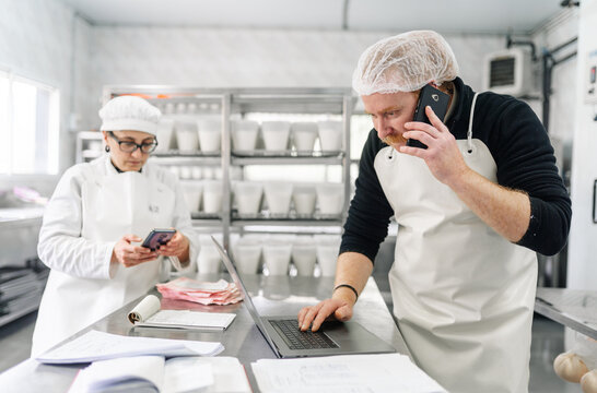 Artisan cheesemakers managing dairy business operations in factory