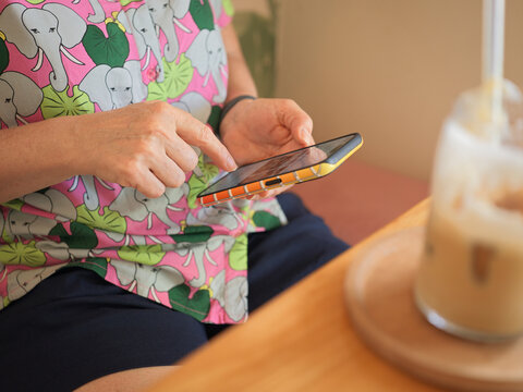Person Uses Smartphone in Cafe While Enjoying Drink