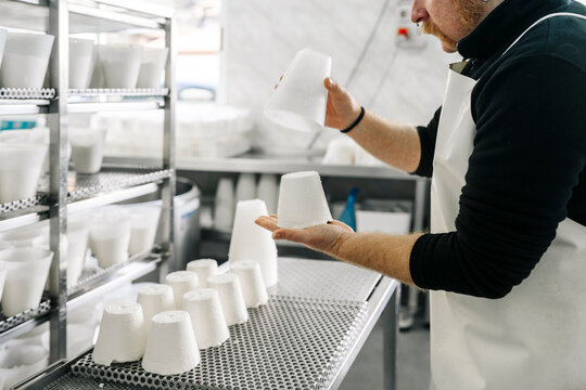 Artisan cheesemaker preparing fresh ricotta cheese in dairy factory