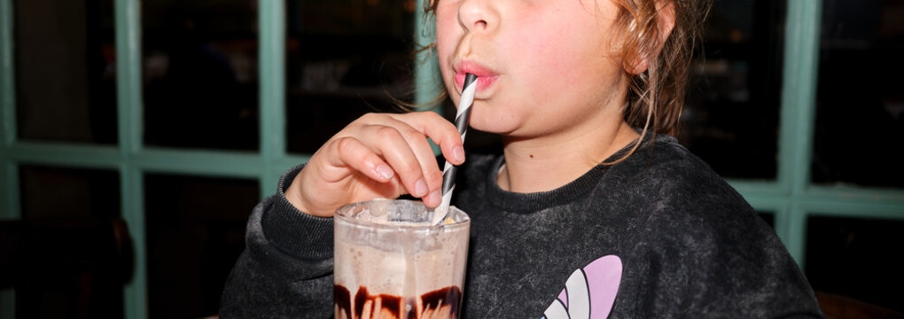 Young child enjoying chocolate milkshake through a straw