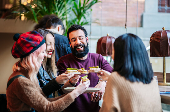 Friends sharing appetizers and laughing at restaurant