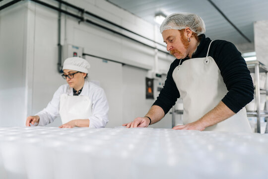 Artisan cheesemakers preparing molds in a small factory