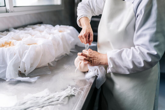 Artisan cheesemaker tying fresh cheese curd in cloth