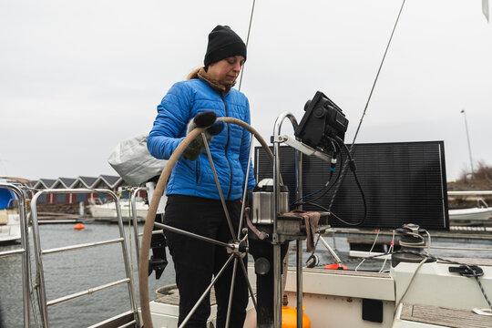 Female Sailor Standing at the Helm and Steering Wheel of a Yacht