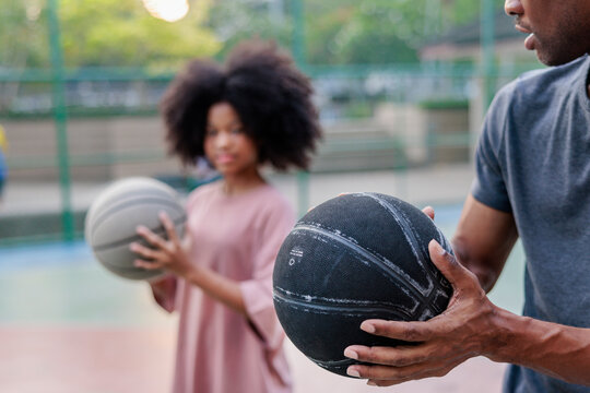 People with basketballs on an outdoor court.