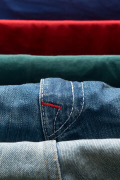 denim jeans detail on drying rack with colorful fabric background
