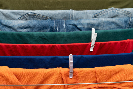 Colorful clothes clipped on drying rack with denim