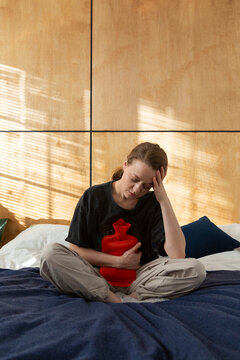 Person relaxing with heating pad experiencing abdominal discomfort