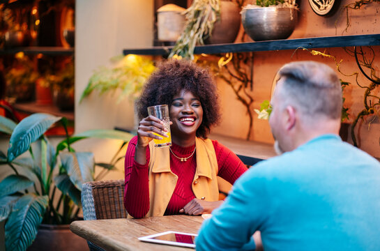 Happy african american woman laughing with partner at restaurant