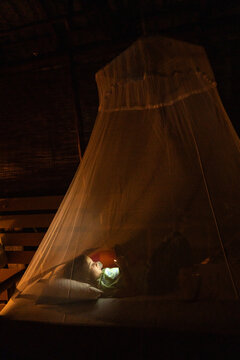 Child Reading Under a Mosquito Net at night