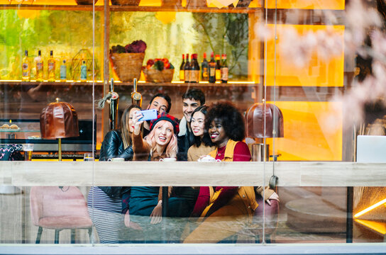 Diverse young friends taking selfie at bar restaurant