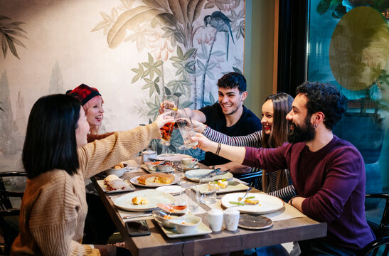 Group of friends toasting, celebrating dinner in a restaurant