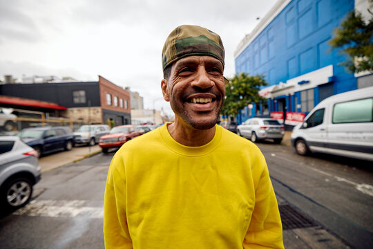 Smiling man stands in the middle of the street in Brooklyn