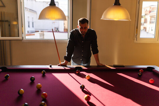 Man standing and observing billiard table at home