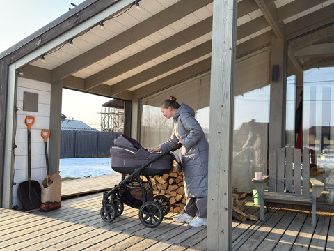 Woman caring for baby by stroller on porch deck