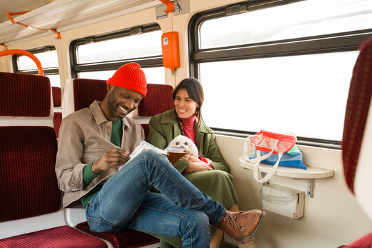 Couple Enjoys Time Together With Dog And Book on Train Journey