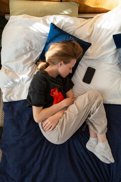 Person lying in bed applying heat pack for discomfort
