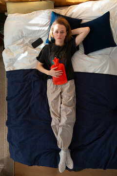 Person finding period pain relief using hot water bottle