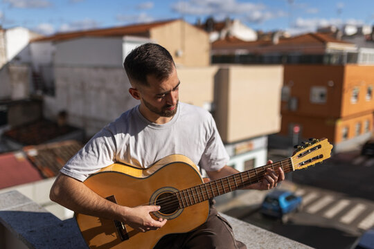 Man playing spanish guitar in bright attic at home