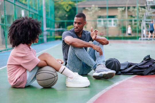 Basketball court conversation, two people sitting, talking,