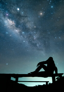 Person contemplating milky way galaxy and starry night sky