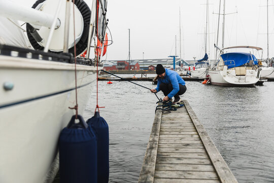 Woman Sailor Mooring Sailboat to Wooden Dock in Marina