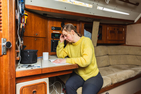 Woman Sailor Studying Navigation Charts in Sailing Boat Cabin