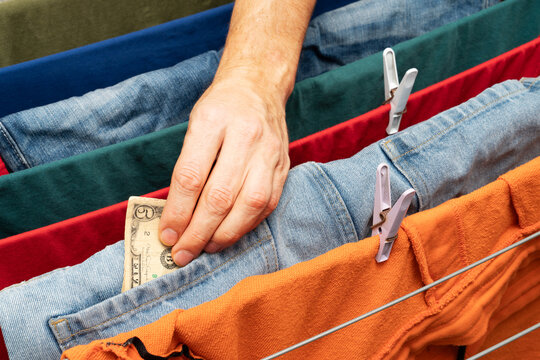 Hand placing money into denim pocket on clothesline