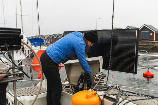 Female Sailor Stowing Equipment in Deck Locker on Boat at Harbor