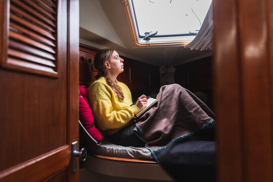 Young Woman Writing in Notebook Inside Sailboat Cabin