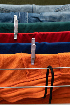 Colorful clothes clipped on drying rack with denim layers