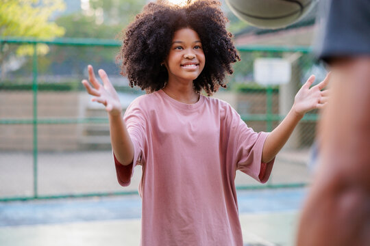 Girl smiles, ready to catch basketball.