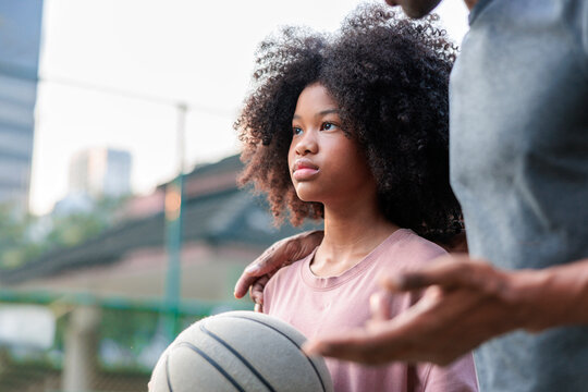 Father and daughter with basketball, sharing a moment.