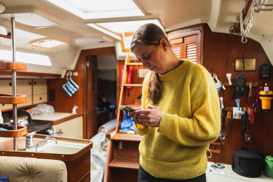 Woman Sailor Using Smartphone for Navigation in Boat Cabin