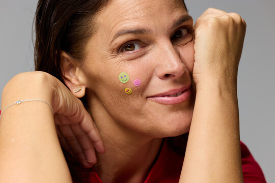 Woman Smiles While Showing Sticker Decorations on Her Face