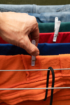Hand clipping orange shorts on drying rack