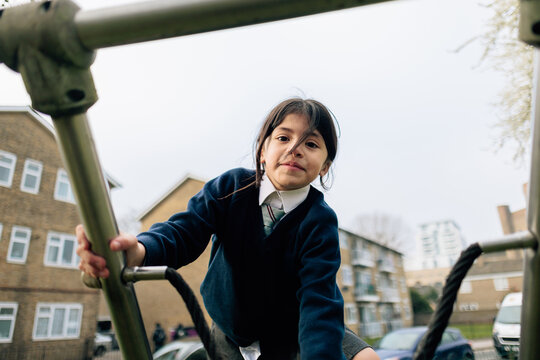 Smiling primary student climbing on playground equipment