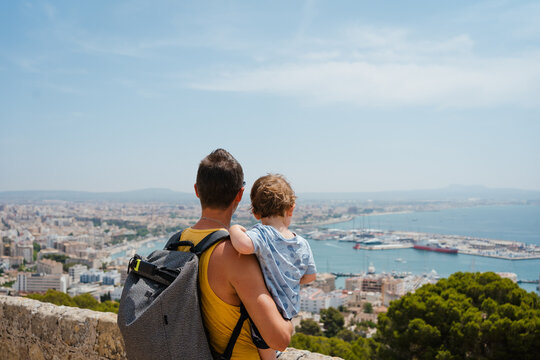 A man and his son are looking at the cityscape from a lookout