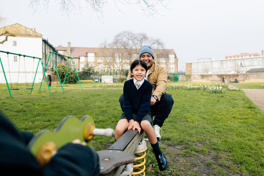 Parent and child playing together on seesaw in playground