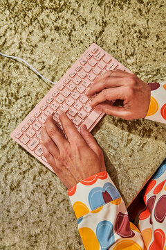 overhead view of a man typing on a pink keyboard
