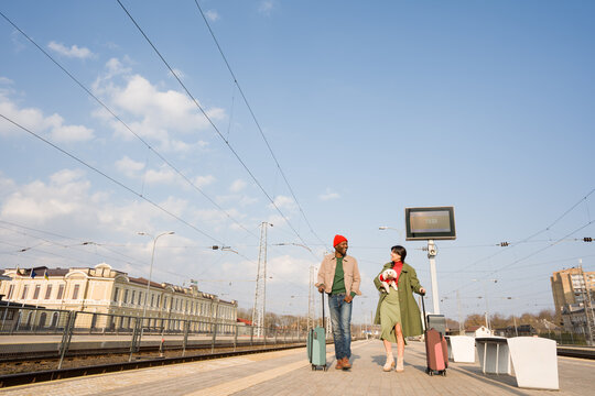 Couple Walking With Dog Under Blue Sky Near Train Tracks